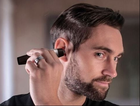 Man using a WAHL Nasal Trimmer by trimming ear hairs.